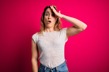Young beautiful blonde woman wearing casual t-shirt standing over isolated pink background surprised with hand on head for mistake, remember error. Forgot, bad memory concept.