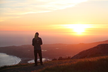 Fototapeta na wymiar silhouette of a man watching sunset over ocean