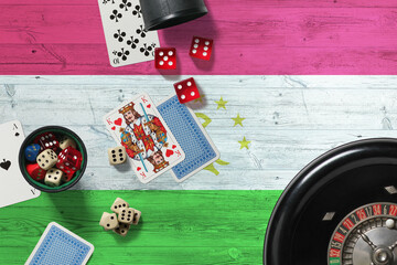 Tajikistan casino theme. Aces in poker game, cards and chips on red table with national wooden flag background. Gambling and betting.