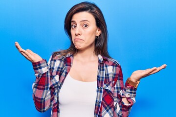 Young beautiful woman wearing casual clothes clueless and confused with open arms, no idea and...