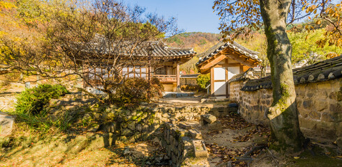 Fototapeta premium Stone wall running to a small oriental tiled roof gate