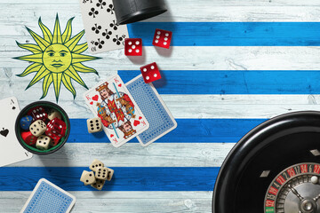 Uruguay casino theme. Aces in poker game, cards and chips on red table with national wooden flag background. Gambling and betting.