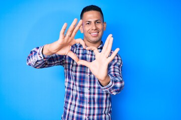 Fototapeta premium Young handsome latin man wearing casual clothes smiling in love doing heart symbol shape with hands. romantic concept.