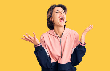 Young beautiful woman wearing sportswear celebrating mad and crazy for success with arms raised and closed eyes screaming excited. winner concept