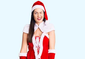 Young beautiful caucasian woman wearing santa claus costume winking looking at the camera with sexy...