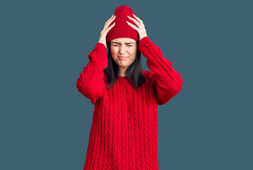 Young beautiful girl wearing sweater and wool cap suffering from headache desperate and stressed because pain and migraine. hands on head.