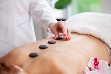 Spa stone massage, beautiful woman getting spa hot stones massage in spa salon.