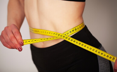 Woman with a sporty figure measures the size of her waist