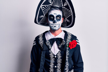 Young man wearing mexican day of the dead costume over white puffing cheeks with funny face. mouth inflated with air, crazy expression.