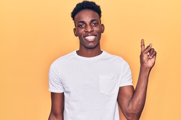 Young african american man wearing casual clothes with a big smile on face, pointing with hand finger to the side looking at the camera.