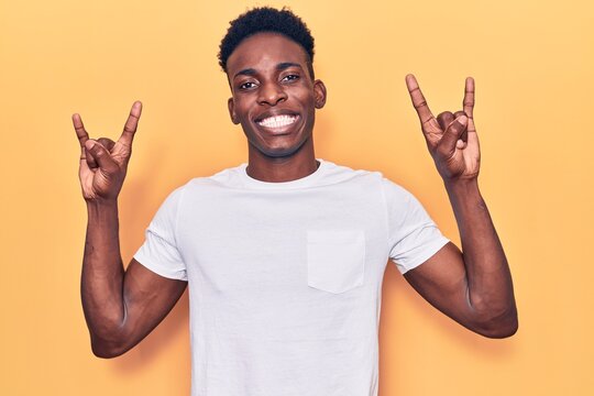 Young african american man wearing casual clothes shouting with crazy expression doing rock symbol with hands up. music star. heavy music concept.