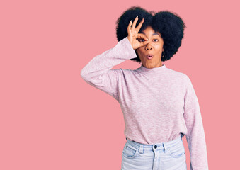 Young african american girl wearing casual clothes doing ok gesture shocked with surprised face, eye looking through fingers. unbelieving expression.