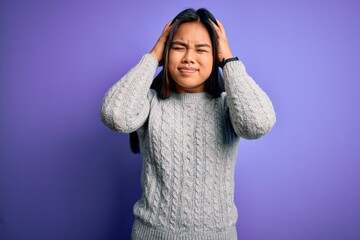 Young beautiful asian girl wearing casual sweater standing over isolated purple background suffering from headache desperate and stressed because pain and migraine. Hands on head.