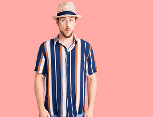 Young handsome caucasian man wearing summer hat afraid and shocked with surprise expression, fear and excited face.