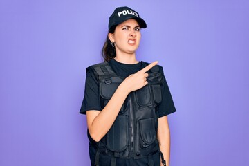 Young police woman wearing security bulletproof vest uniform over purple background Pointing aside worried and nervous with forefinger, concerned and surprised expression
