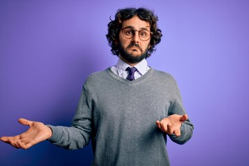 Handsome businessman with beard wearing tie and glasses standing over purple background clueless and confused expression with arms and hands raised. Doubt concept.