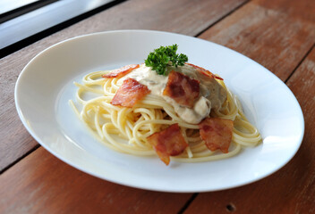 Delicious spaghetti carbonara with bacon on wooden table