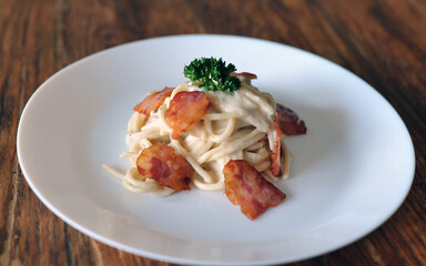Delicious spaghetti carbonara with bacon on wooden table