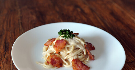 Delicious spaghetti carbonara with bacon on wooden table