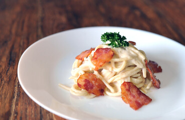 Delicious spaghetti carbonara with bacon on wooden table