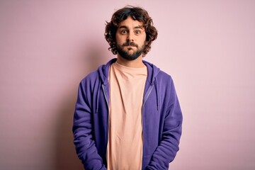 Young handsome sporty man with beard wearing casual sweatshirt over pink background puffing cheeks with funny face. Mouth inflated with air, crazy expression.