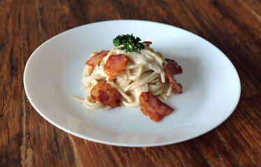 Delicious spaghetti carbonara with bacon on wooden table