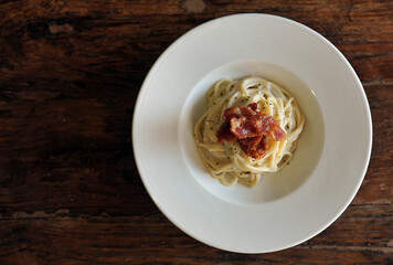 Delicious spaghetti carbonara with bacon on wooden table