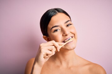 Young beautiful brunette woman brushing her teeth using tooth brush and oral paste, cleaning teeth...
