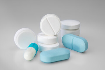White and blue tablets and pills on a light background. Medical concept. Selective focus