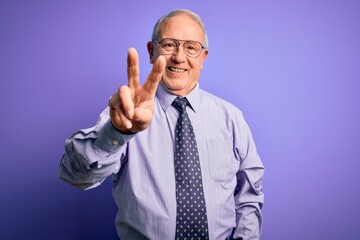 Grey haired senior business man wearing glasses standing over purple isolated background showing and pointing up with fingers number two while smiling confident and happy.
