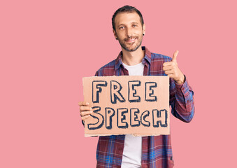 Young handsome man holding free speech banner smiling happy and positive, thumb up doing excellent and approval sign