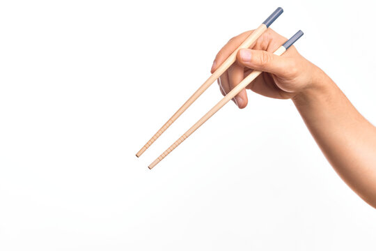 Hand of caucasian young man holding chopsticks over isolated white background