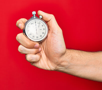 Beautiful hand of man holding stopwatch doing countdown over isolated red background