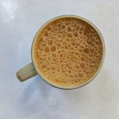A cup of teh tarik also known as pulled tea on white background.It is a popular hot milk tea beverage and national drink of Malaysia.
