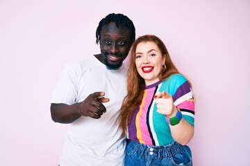 Interracial couple wearing casual clothes pointing fingers to camera with happy and funny face. good energy and vibes.