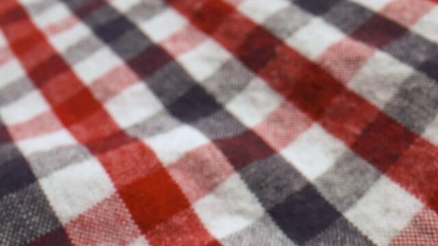 Close up slide over a red, white, and blue checked cotton shirt.