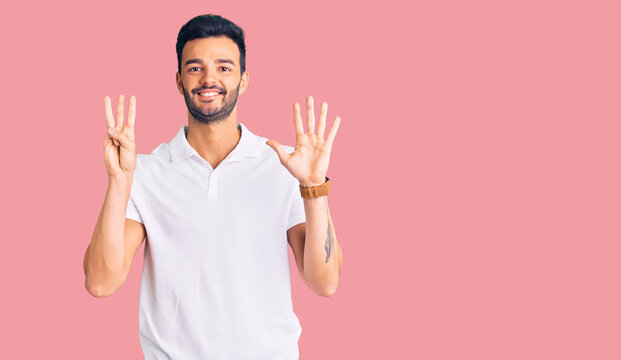 Young handsome hispanic man wearing casual clothes showing and pointing up with fingers number eight while smiling confident and happy.