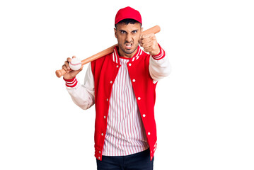 Young hispanic man playing baseball holding bat and ball annoyed and frustrated shouting with anger, yelling crazy with anger and hand raised