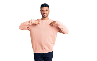 Young hispanic man wearing casual clothes looking confident with smile on face, pointing oneself...