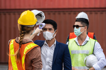 Engineer worker wearing surgical mask checking body temperature using infrared digital thermometer check temperature before into workplace, workers with protective mask