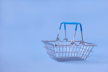 Empty metal shopping basket on a blue background