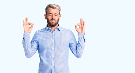 Young handsome blond man wearing elegant shirt relaxed and smiling with eyes closed doing meditation gesture with fingers. yoga concept.