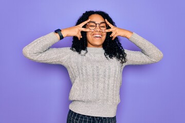 Young african american woman wearing casual sweater and glasses over purple background Doing peace symbol with fingers over face, smiling cheerful showing victory