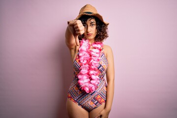 Young beautiful arab woman on vacation wearing swimsuit and hawaiian lei flowers looking unhappy and angry showing rejection and negative with thumbs down gesture. Bad expression.