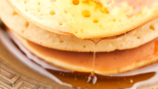 Sweet bee honey drips slowly over pancakes 