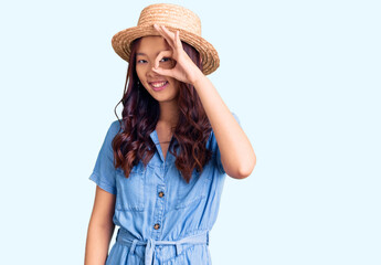 Young beautiful chinese girl wearing summer hat doing ok gesture with hand smiling, eye looking through fingers with happy face.