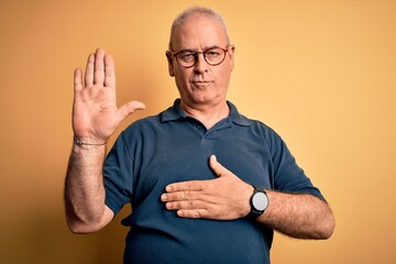 Middle age handsome hoary man wearing casual polo and glasses over yellow background Swearing with...