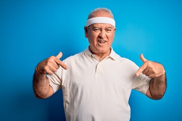 Middle age hoary sportsman doing sport wearing sportswear over isolated blue background looking...
