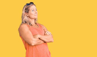 Obraz premium Middle age fit blonde woman wearing casual summer clothes and sunglasses looking to the side with arms crossed convinced and confident
