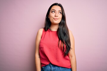 Fototapeta premium Young brunette woman wearing casual summer shirt over pink isolated background smiling looking to the side and staring away thinking.